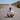 Man sitting on an empty road wearing an AMOR MARIS T-shirt and a cap with landscape in the background.